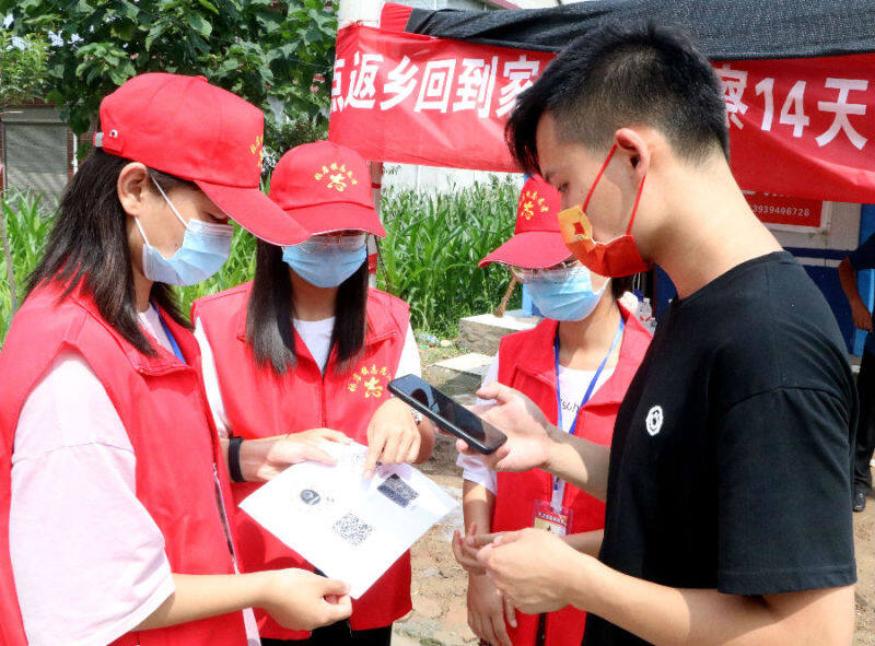 大学生志愿者在村口卡点引导过往村民扫码(于新豪 摄)