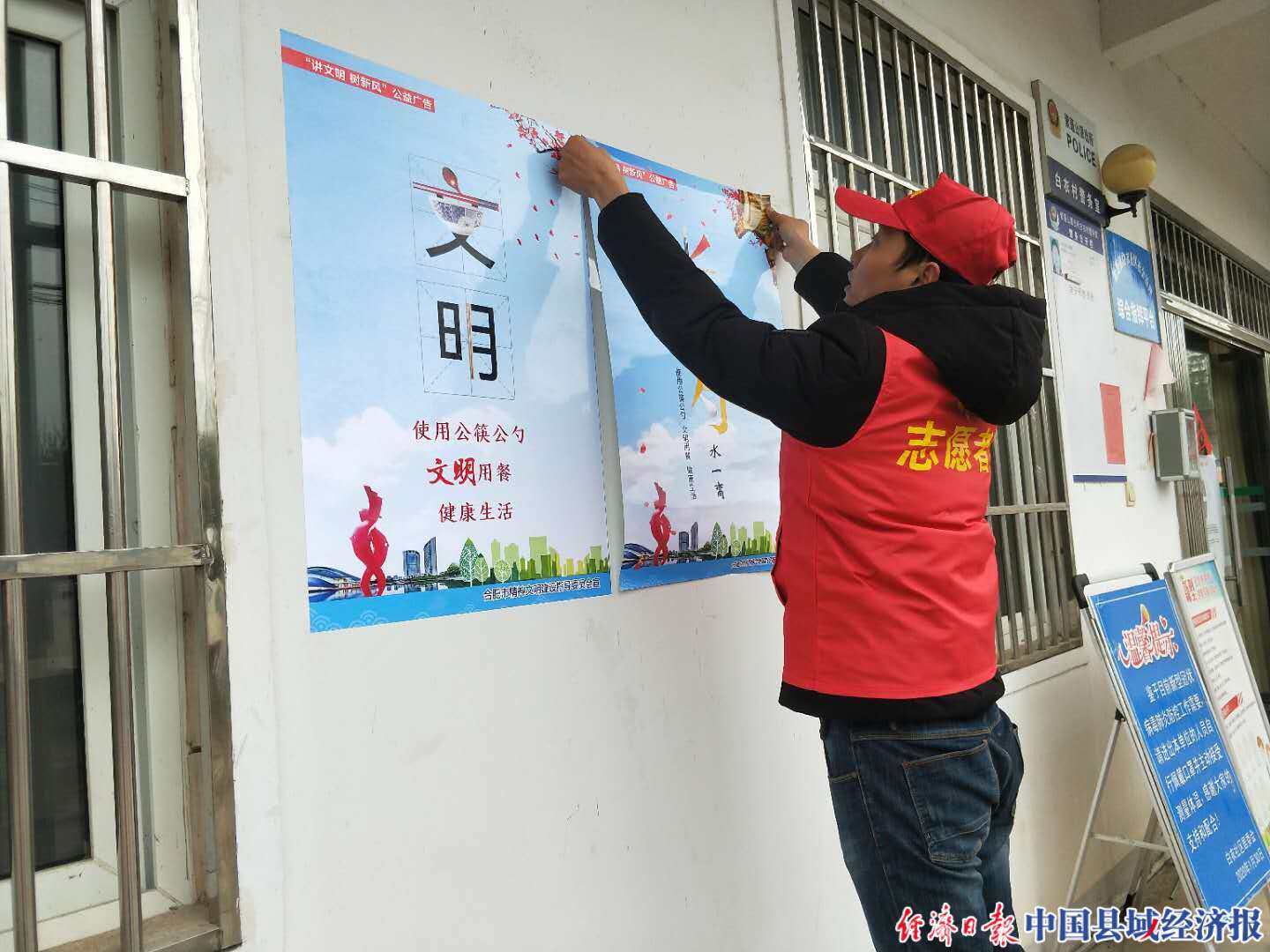 该镇白衣社区文明实践所正在张贴"文明用餐"公益广告