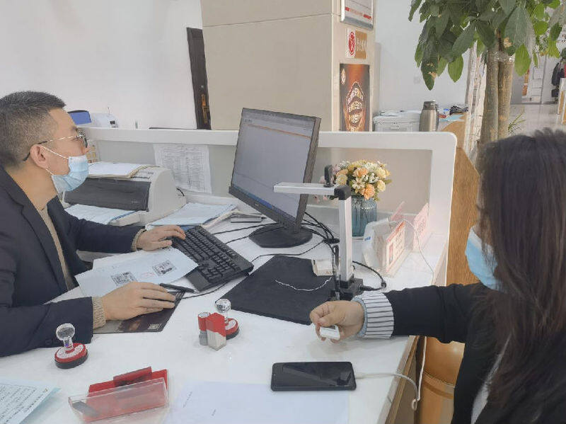 业务人员为客户办理手机银行业务(王磊 摄)