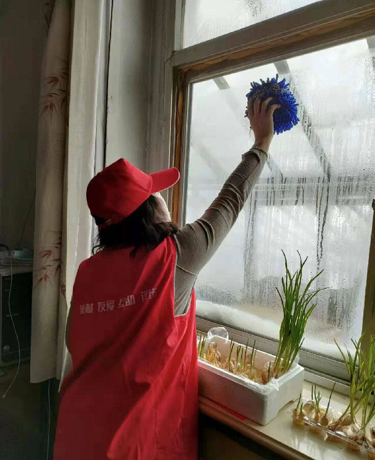 志愿者们为残疾人家擦玻璃(牛丽红 摄)