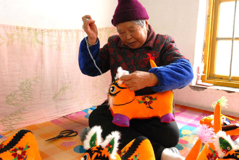 西太祉庄村的民间艺人孙正开在家里赶制“布老虎” 布偶。（张涛 摄）