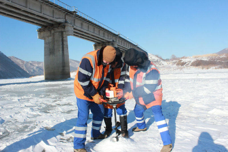 工人在使用内燃钻孔机进行冰面钻孔作业（吕金奎 摄）