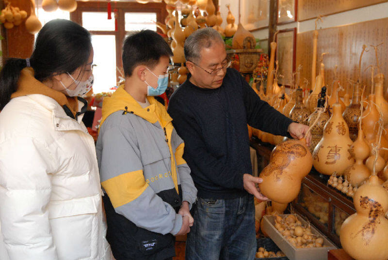 1月21日，即墨古城葫芦烙画展览室，黄旭向游客介绍葫芦烙画作品。（张涛 摄）