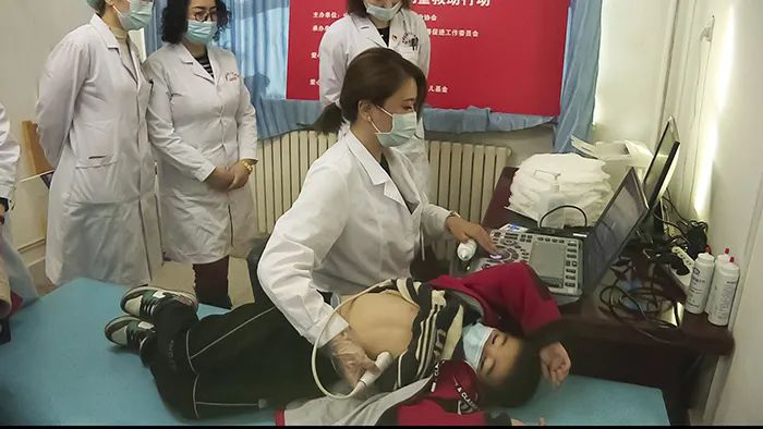 图为新疆维吾尔自治区人民医院专家用心脏彩超给疑似患儿检查身体(穆