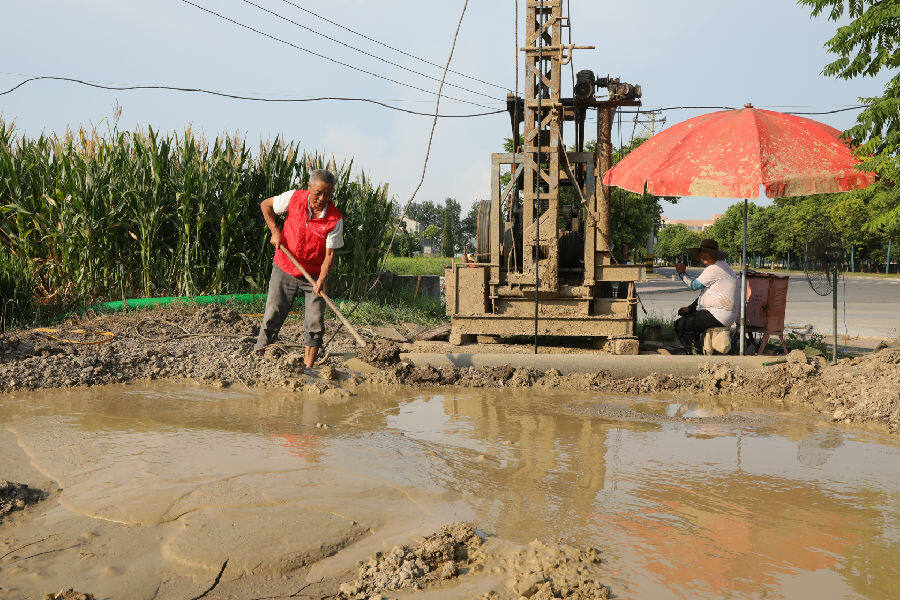 图为身穿"红马甲"志愿者忙着帮村民们打机井(李勤 摄)