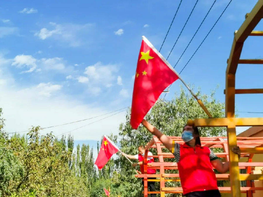 图为志愿者在杭桂镇幸福村帮助村民挂国旗（热依汗古丽·阿卜力米提 摄）