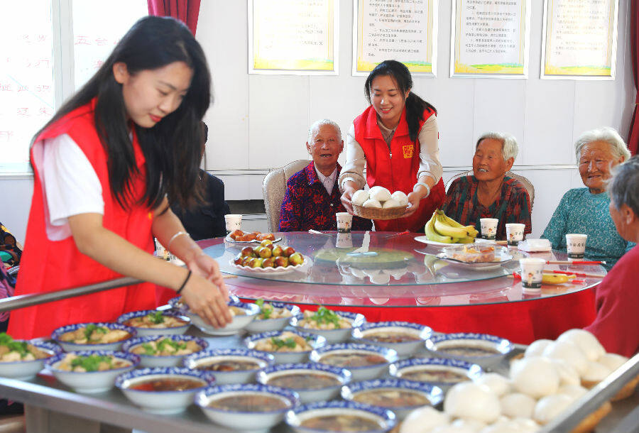 2022年9月30日，山东省乐陵市杨安镇万安居新村暖心食堂，志愿者为老人们端上热乎乎的免费午餐。（贾鹏 摄）