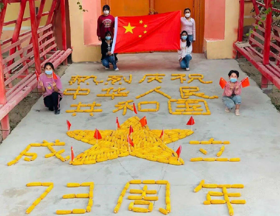 图为洛浦县杭桂镇巴什艾克尼村村民与国旗合影，祝福祖国。（阿卜杜帕塔尔·阿卜来 摄）