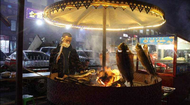 图为库车市乌恰镇彩虹综合市场夜市内商户在制作烤鱼.(樊凯 摄)