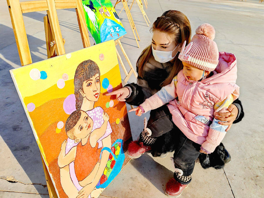 图为温宿县克孜勒镇村民带着孩子观看农民画展(玛依拉·阿卜来提 摄)