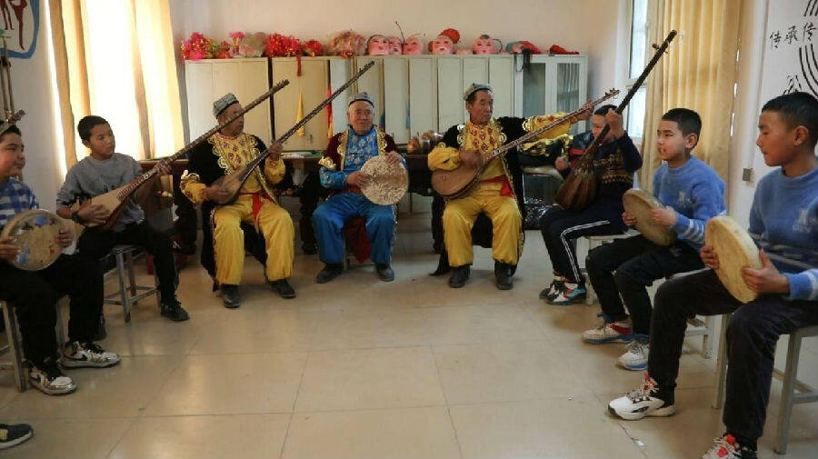 非物质文化遗产传承人教孩子们学习都塔尔(韩遇琳 摄)