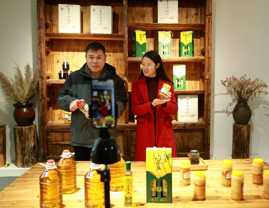 图为蒙昌明（左）正在直播销售农副产品（唐慧芳 摄）
