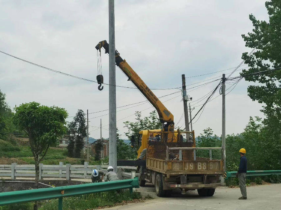 电力施工人员安装电线杆子(田维 摄)