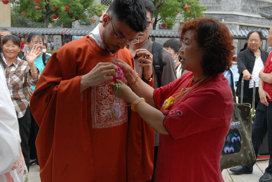 居民向外国友人佩戴象征健康平安的香囊(张涛 摄)