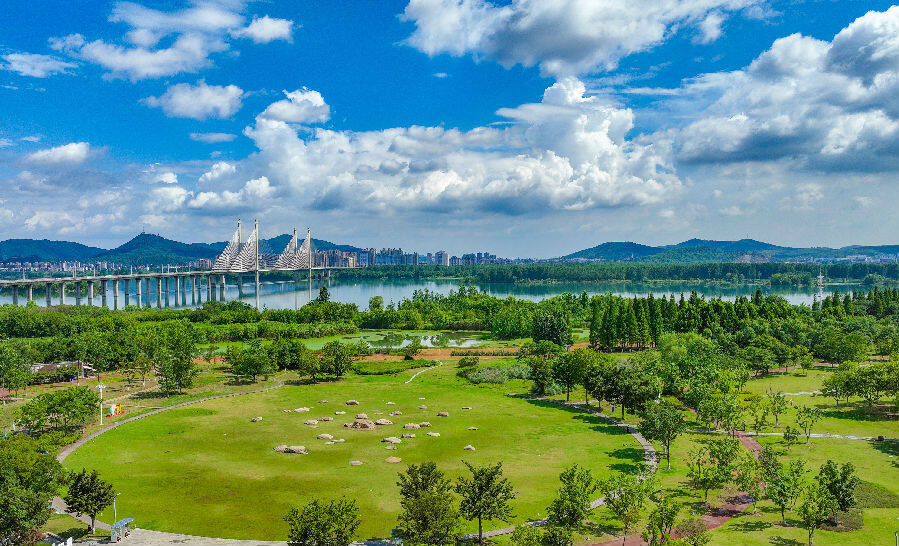 图为雨过天晴,月亮湾湿地公园在蓝天白云的映衬下绿意盎然,风景宜人.