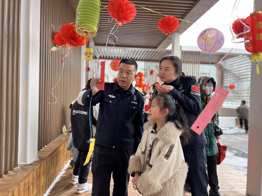 摄)灯谜区悬挂了一个个红彤彤的灯笼,现场30多条谜语涵盖了生活常识