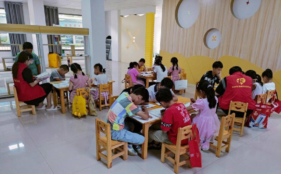 图为郧西县马安镇社工、大学生志愿者辅导孩子们写作业（朱小美 摄）
