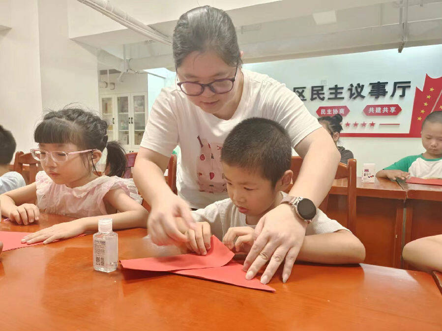 志愿者指导孩子们折纸鹤（刘钦赐 摄）