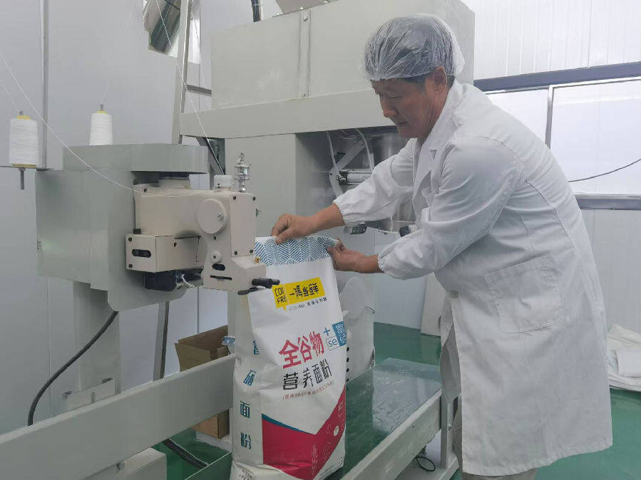 王军示范对富硒全谷物营养面粉进行塑封包装（秦笑波 摄）