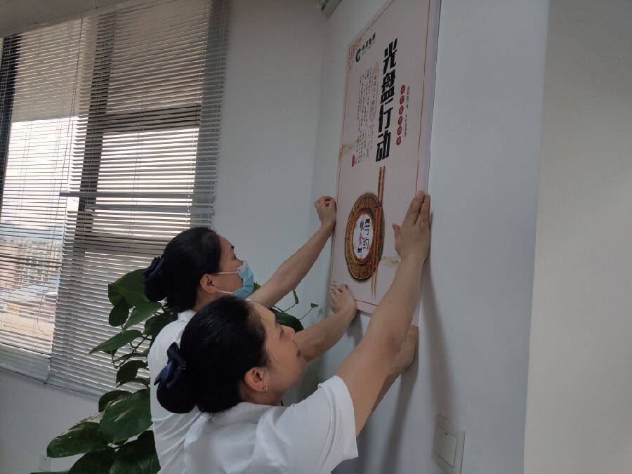 图为桂林烟草食堂工作人员粘贴“光盘行动”就餐提示牌（蒋海丽 摄）