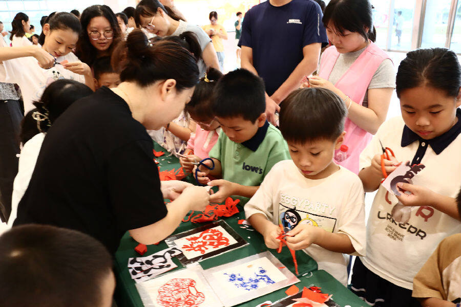 在教师指导下，孩子们学习剪纸。（蓝心湄 摄）
