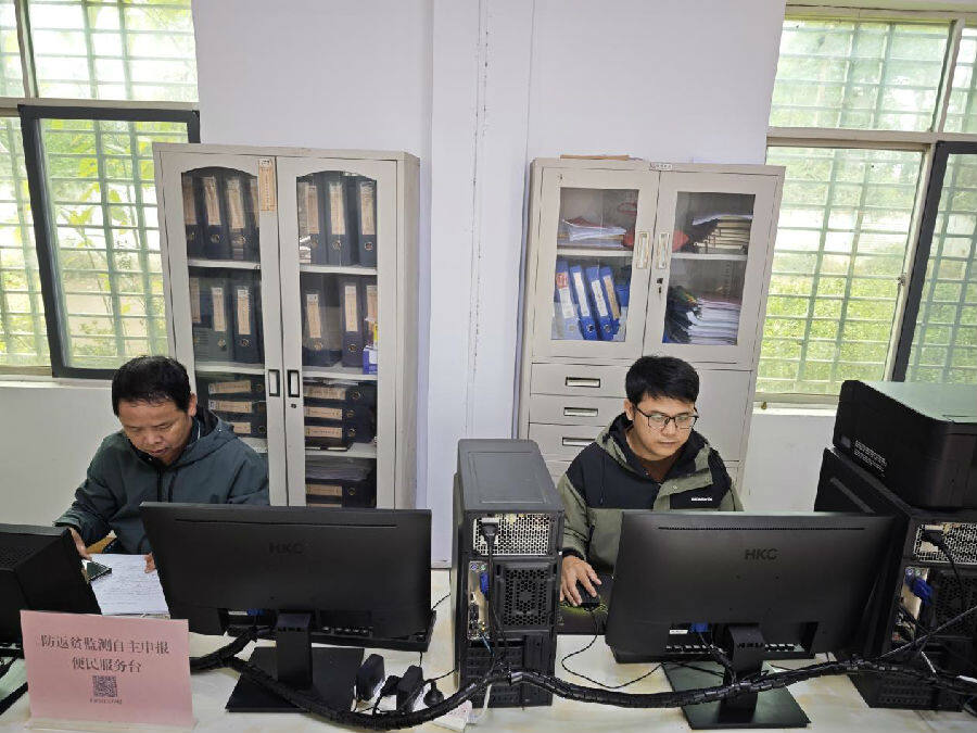 吴不达（右）在多贤村委会办公室为困难学子申请教育补助（王朝坚 摄）