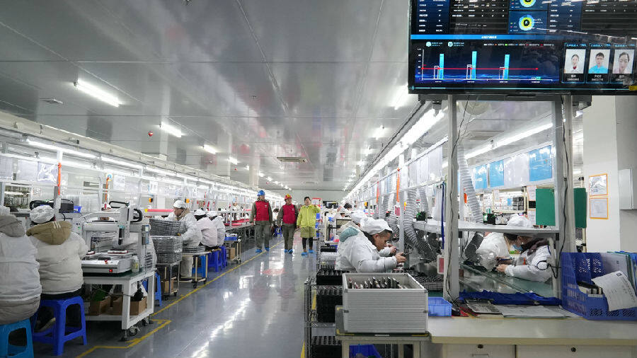 宜城市供电公司员工在敦拓电子公司车间内查看用电设备运行情况，了解企业用电需求。（梁梦 摄）