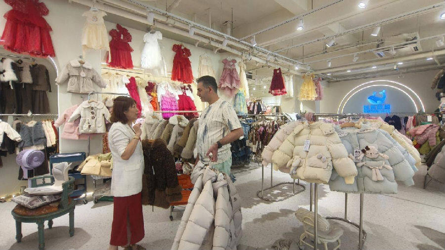 湖州天鲸国际贸易有限公司文晓莉总经理（左）正在和伊朗采购商洽谈冬装现场（曾庆华 摄）