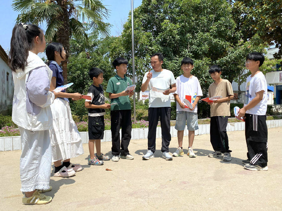 平店乡马庄小学校长刘俊伟向学生发放急救知识宣传材料（赵永昌 摄）