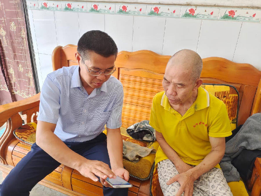 专卖执法人员上门指导群众通过手机端办理许可证事项（李志海 摄）