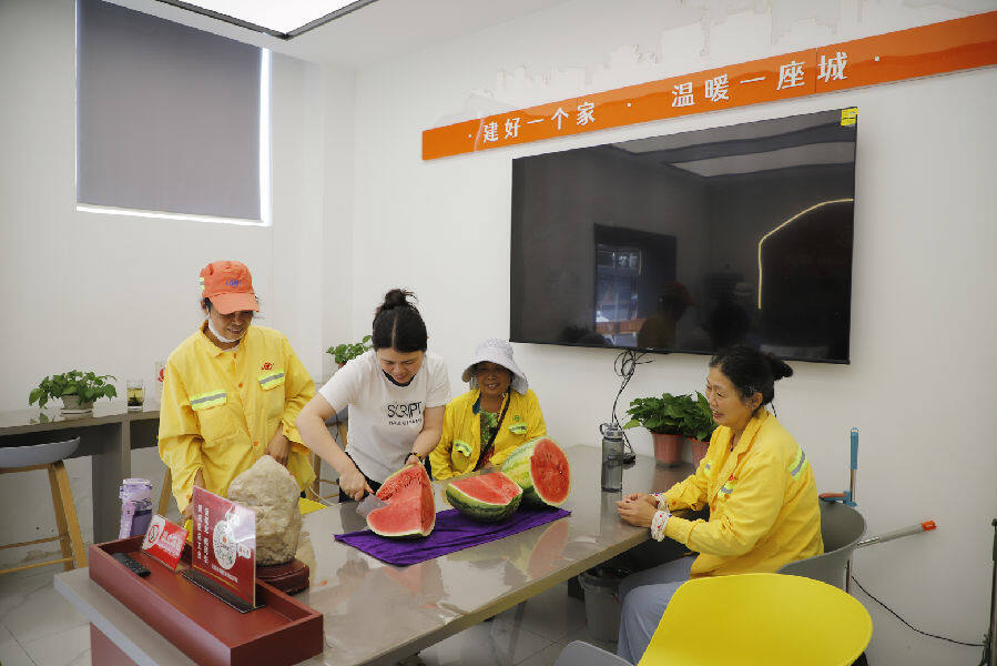 爱心驿站工作人员正在为环卫工人切西瓜，消暑降温。（王晓丽 摄）
