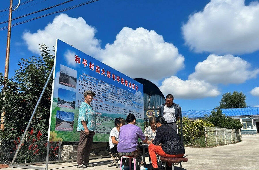 图为村民正在门前娱乐（于海静 摄）
