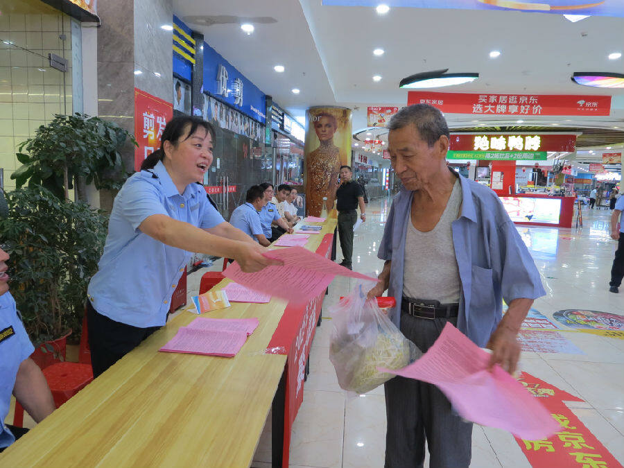 活动现场工作人员为市民宣传解读政策（童曙明 摄）