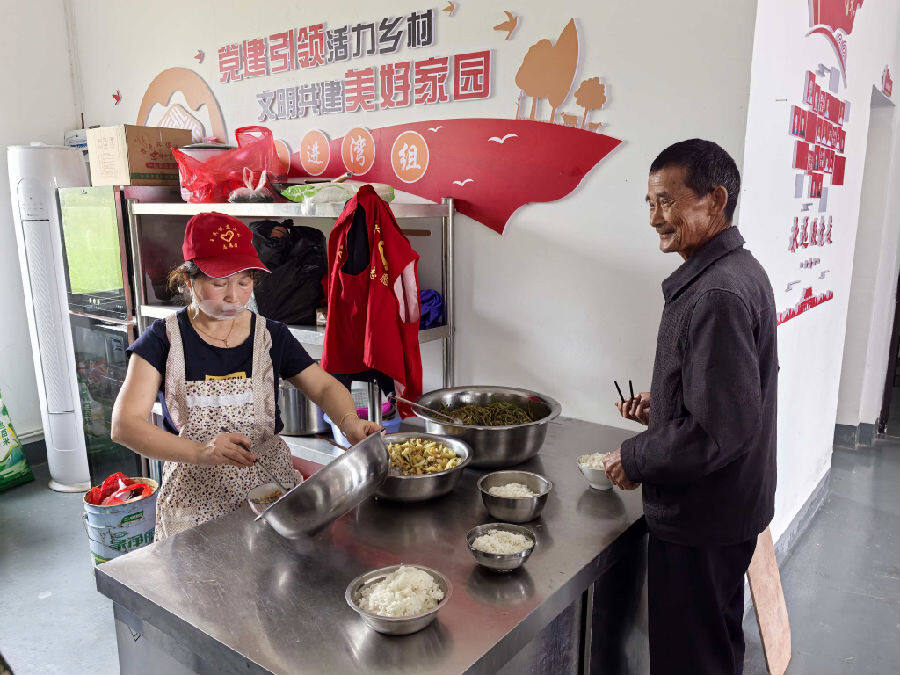 尹先华（左）正在为村民在幸福食堂“服务”（何炟 摄）