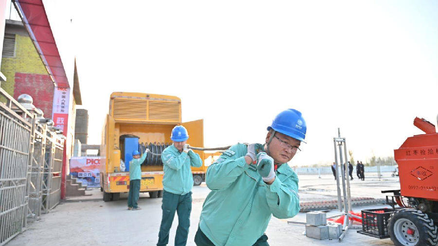 工作人员在有序铺设电缆、检查电气设备，为盛会用电保驾护航。（邸敏 摄）