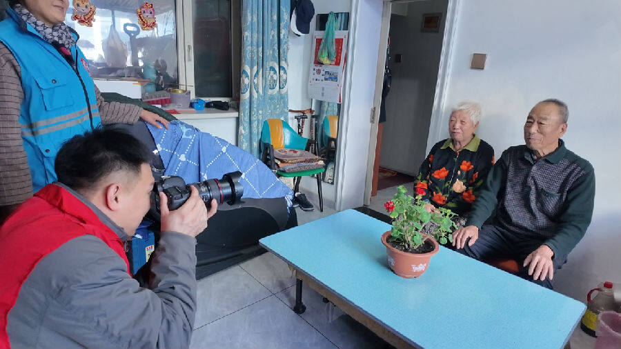 志愿者为老人拍照片（崔倩宁 摄）